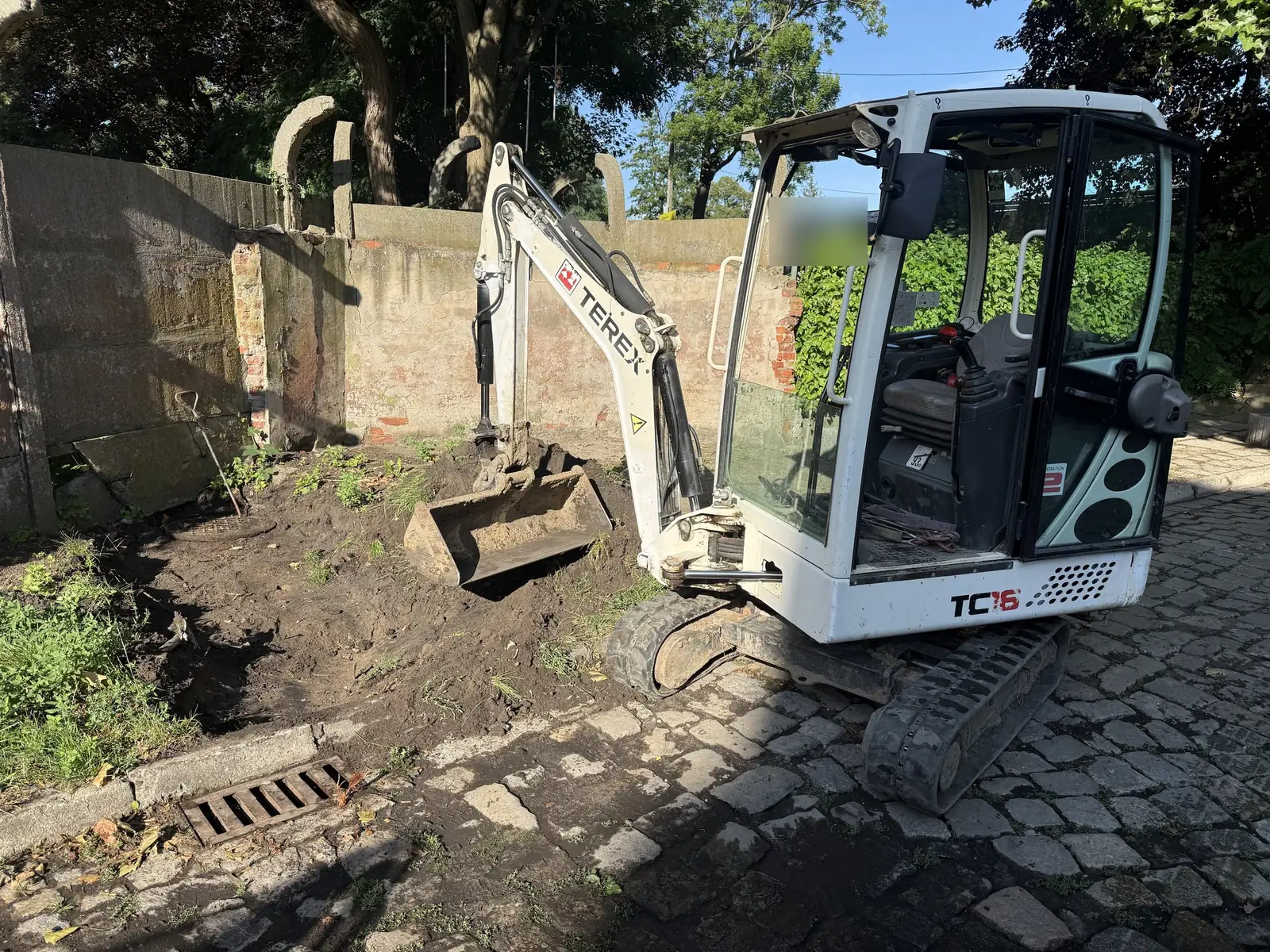 Minikoparka Terex TC16 wykonuje wykop pod nowy wpust deszczowy